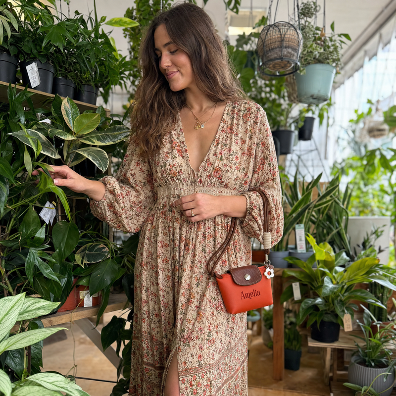 Woman carrying a personalized small coin pouch with custom name in a garden