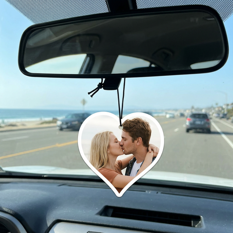 Heart-shaped personalized couple photo ornament hanging from a car rearview mirror