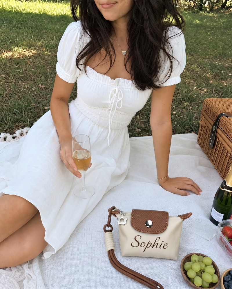 Woman relaxing outdoors with a personalized brown mini pouch featuring custom name Sophie