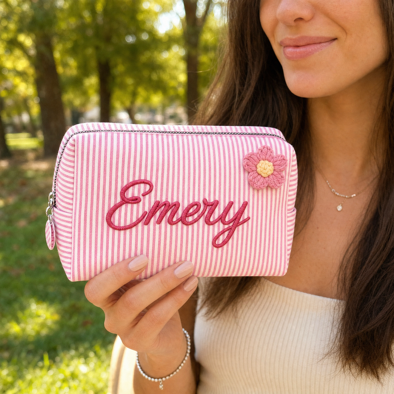 Woman holding a personalized pink striped makeup bag with custom name Emery outdoors