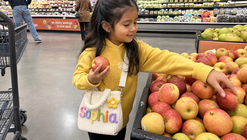 Girl carrying a personalized tote with custom name Sophia while grocery shopping